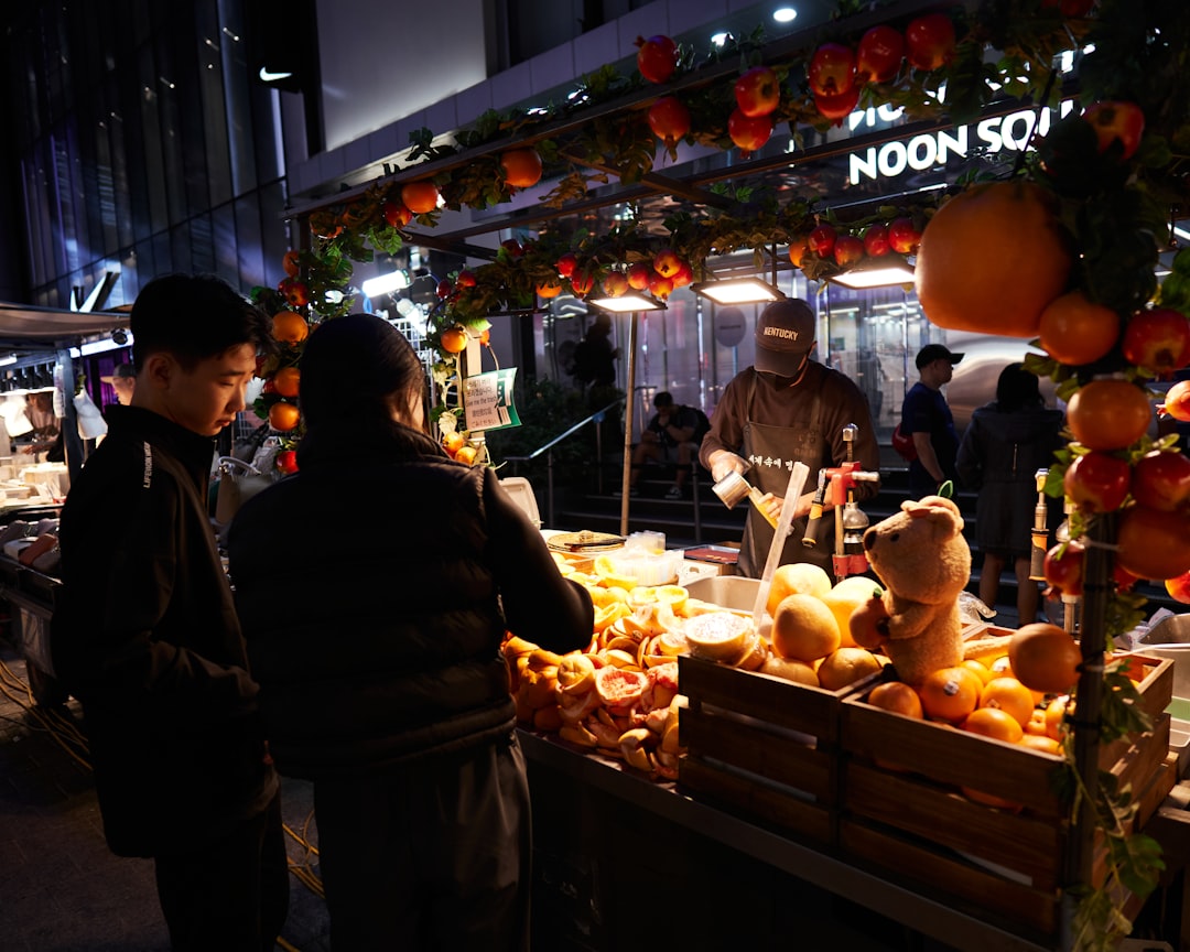 a group of people standing around a fruit stand