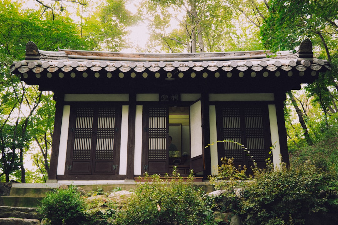 Small traditional building surrounded by lush green trees.