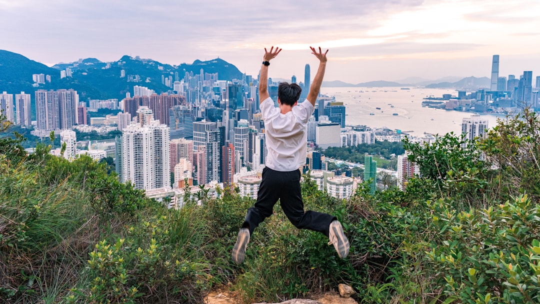 Man jumping with arms raised overlooking city skyline.