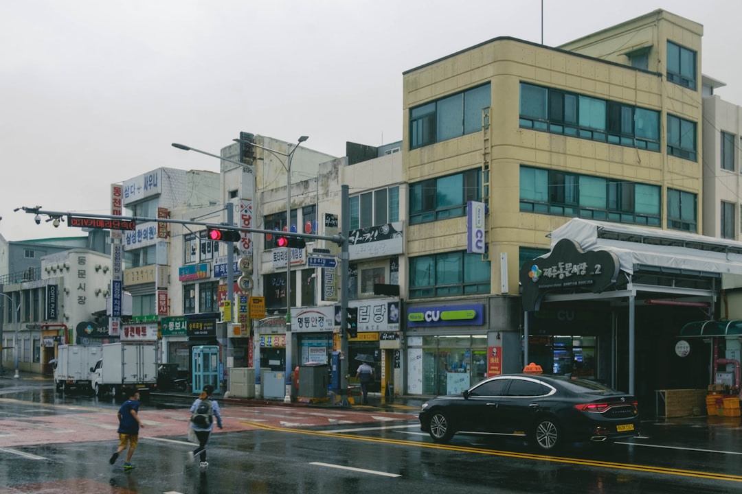 a couple of people crossing a street in the rain
