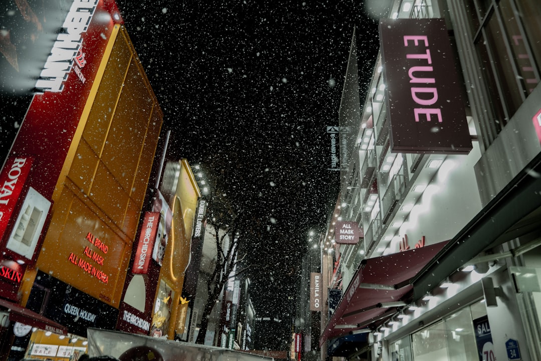 Snow falls on a city street at night.