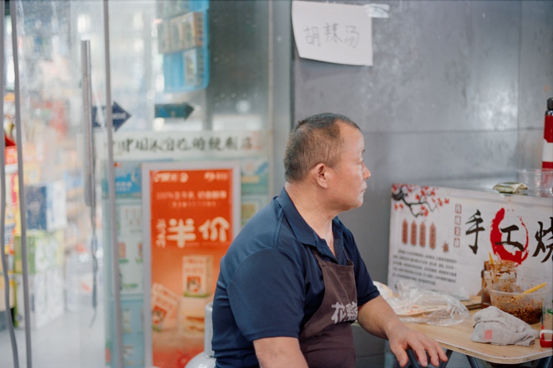 Man sitting in front of a store with chinese writing.