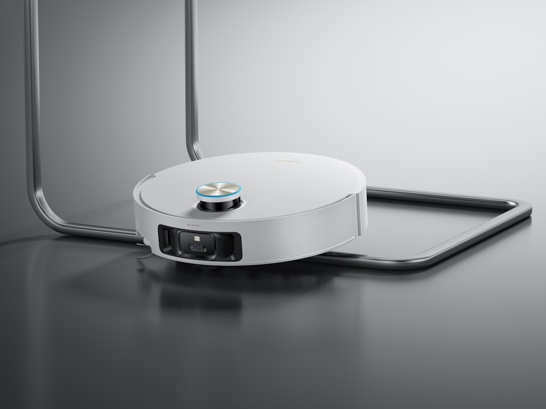 A white robotic vacuum cleaner on a metallic surface.