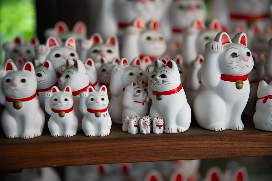 Many white lucky cat figurines on a wooden shelf